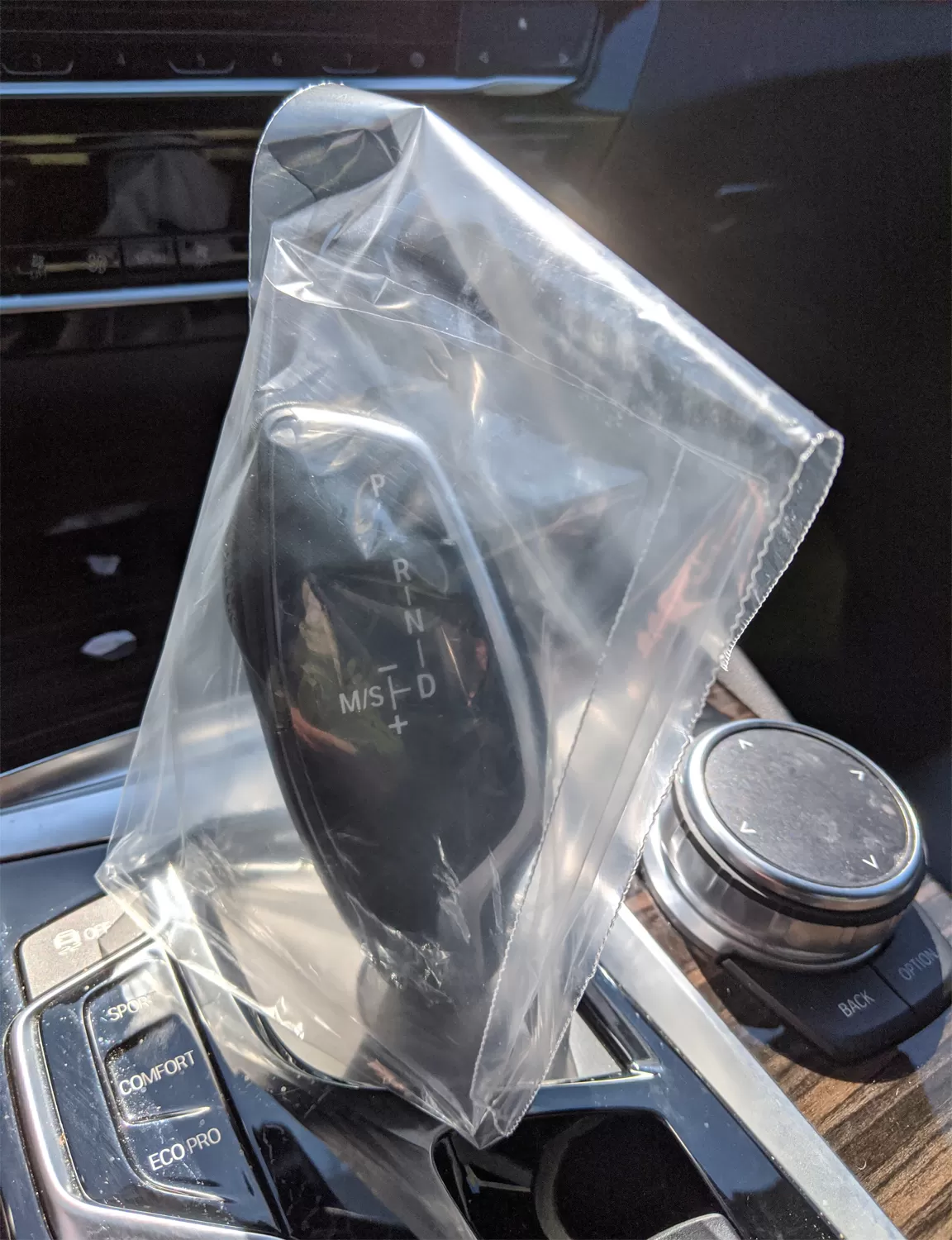 Clear disposable plastic gear shift cover protecting a vehicle gearshift
