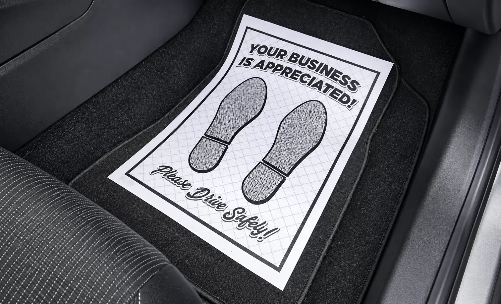 Ridged white paper floor mat with black footprints and Your Business Is Appreciated message